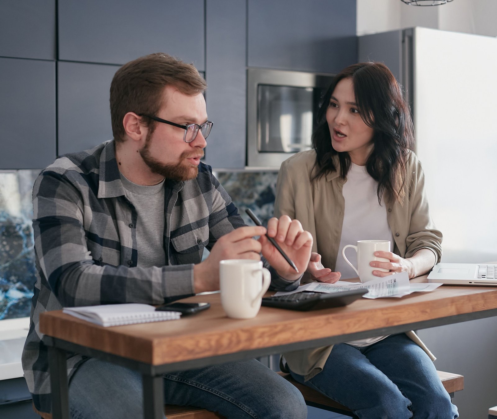 Two people at a kitchen table reviewing bills and planning where extra side hustle income will go